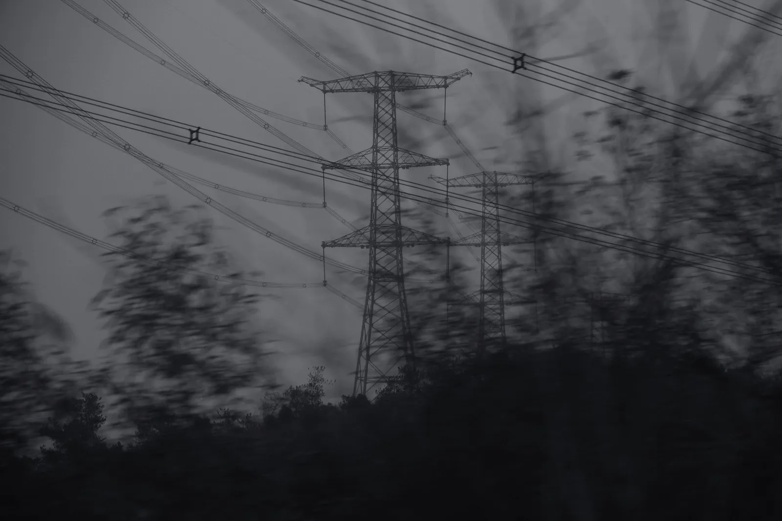 Silhouette of transmission towers against the sky in a grayscale monochrome setting, creating a dramatic effect. Stock photo illustrating Viviana Power Tech's earning call story.