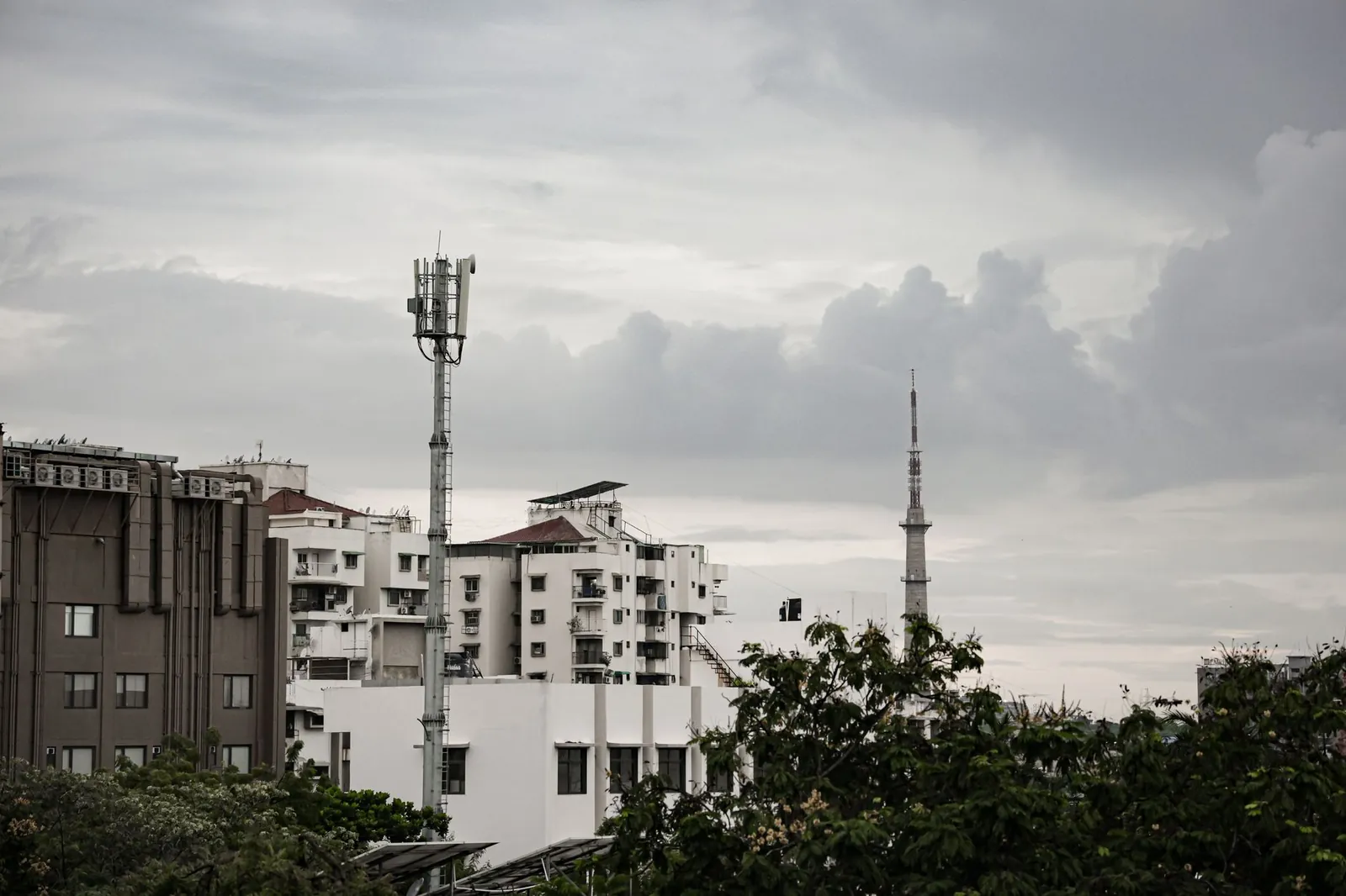Urban skyline of Ahmedabad featuring a telecommunications tower and grey clouds. Stock photo illustrating Bharti Airtel's expansion story.