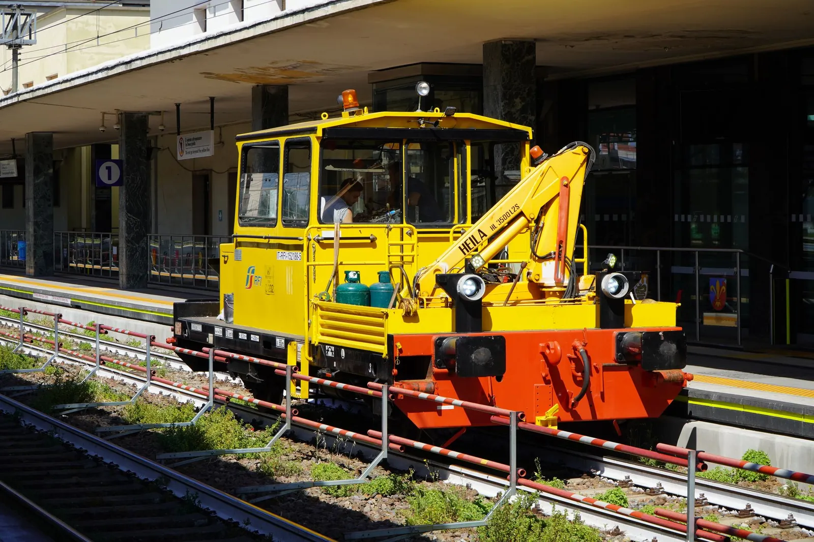 A bright yellow railway maintenance vehicle on tracks at a modern train station. Stock photo illustrating GHV Infra Projects' new order story.