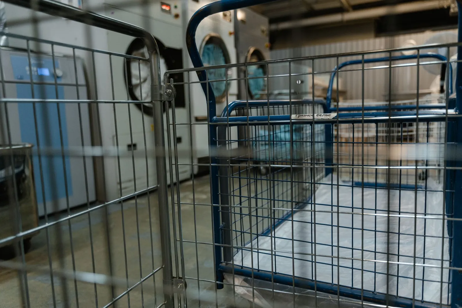 Empty metal baskets and commercial washing machines in a laundry facility. Stock photo illustrating Avio Smart Market Stack's expansion story.