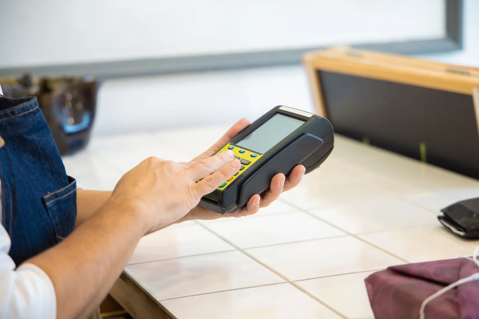 Close-up of hands using a POS machine in a retail setting, emphasizing digital payment. Stock photo illustrating Pine Labs' financial results story.