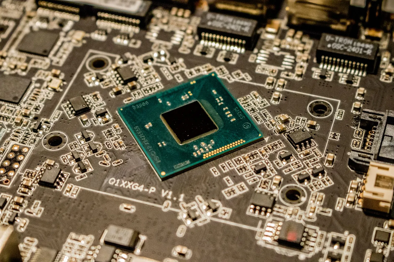 Detailed view of a microchip on a printed circuit board, showcasing electronic components. Stock photo illustrating Cyient's fund raise story.