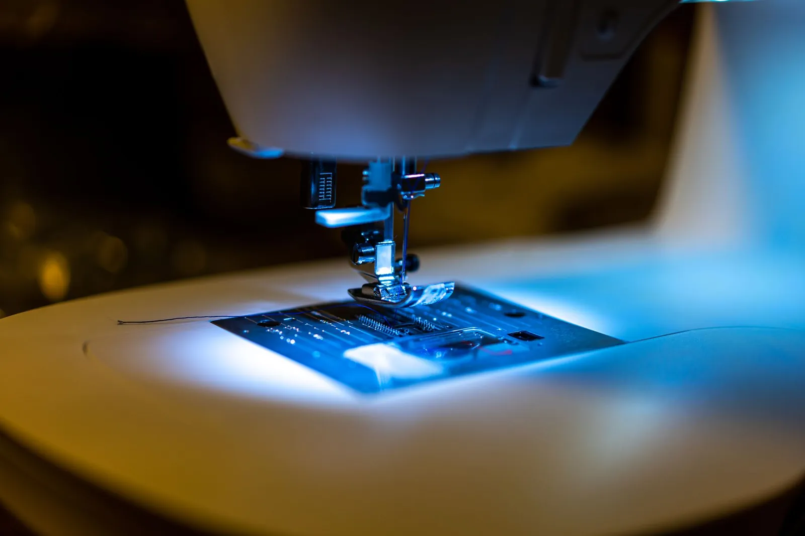 Detailed view of a sewing machine's needle area with LED lighting, highlighting modern technology. Stock photo illustrating Virtuoso Optoelectronics' fund raise story.