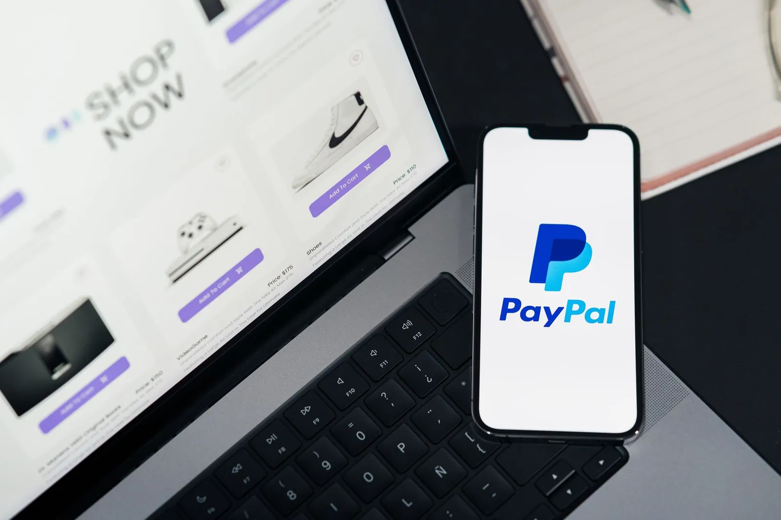 Smartphone displaying PayPal logo next to laptop with online shopping site open. Stock photo illustrating Comfort Fincap's product launched story.