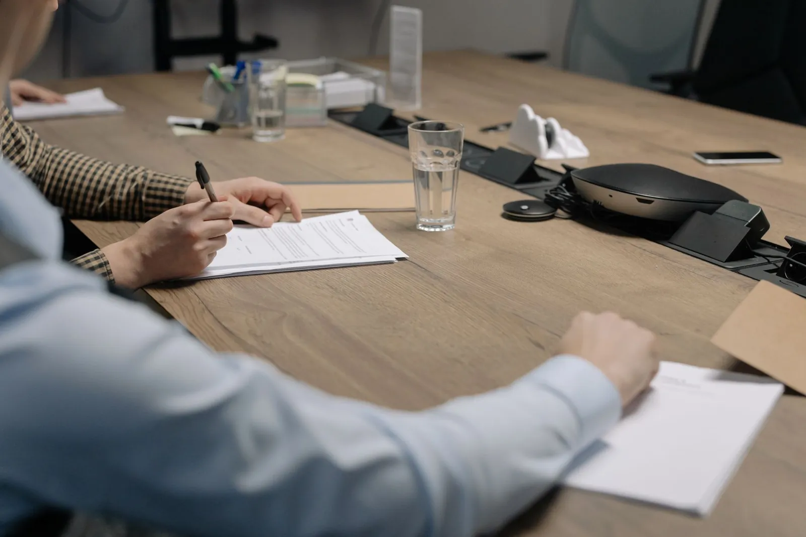 Professional setting of a business meeting with individuals signing documents on a conference table. Stock photo illustrating Paisalo Digital's expansion story.