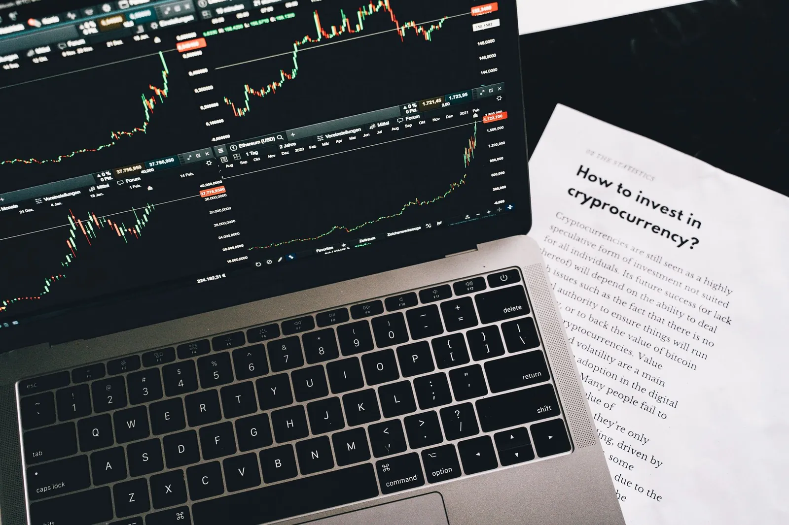 Close-up of a laptop displaying stock market graphs with a paper on investing in cryptocurrency, indoors. Stock photo illustrating Nuvama Wealth Management's regulatory approval story.