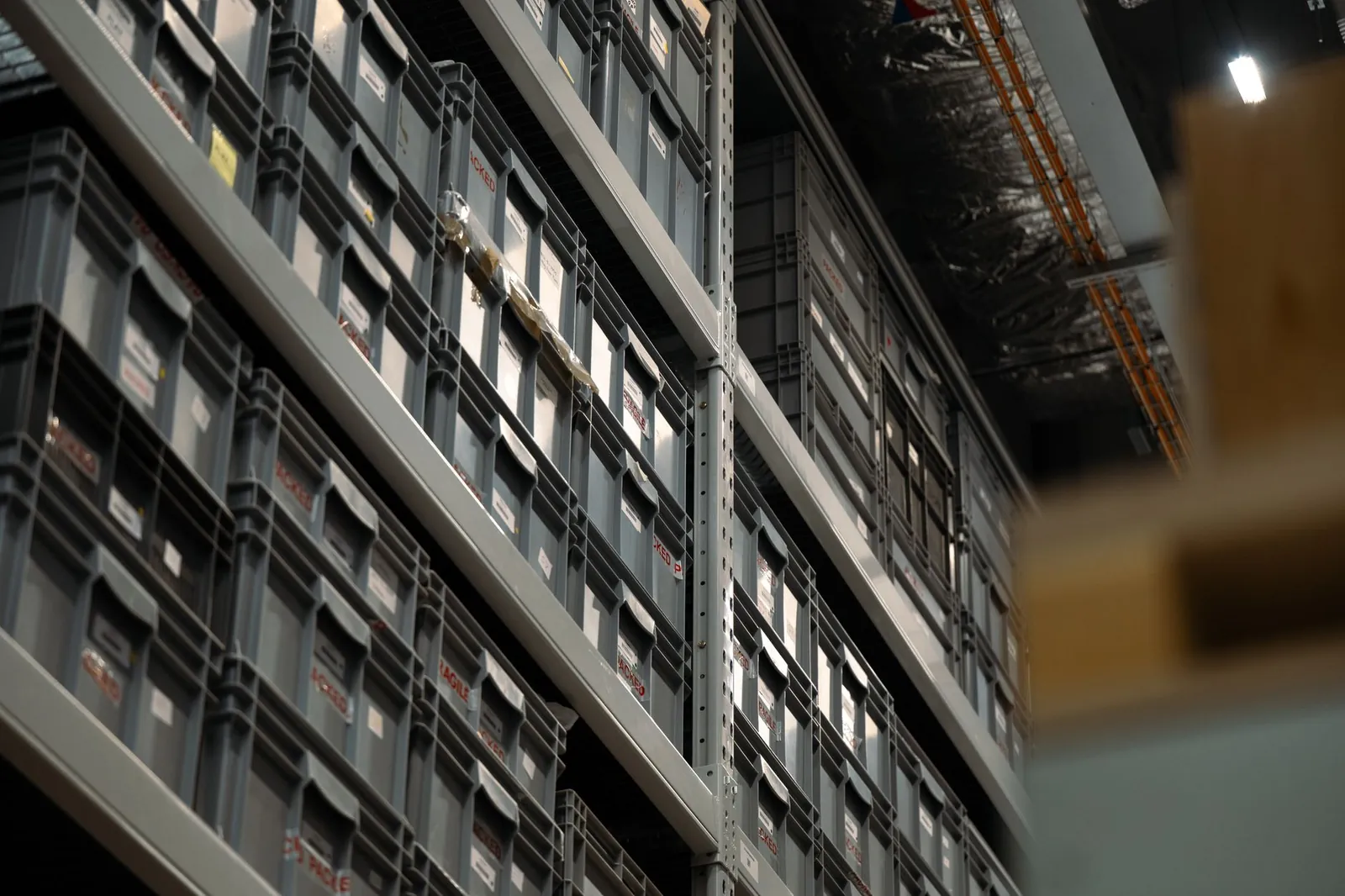 Perspective view of industrial shelves filled with organized plastic storage boxes in a warehouse. Stock photo illustrating SPML Infra's product launched story.