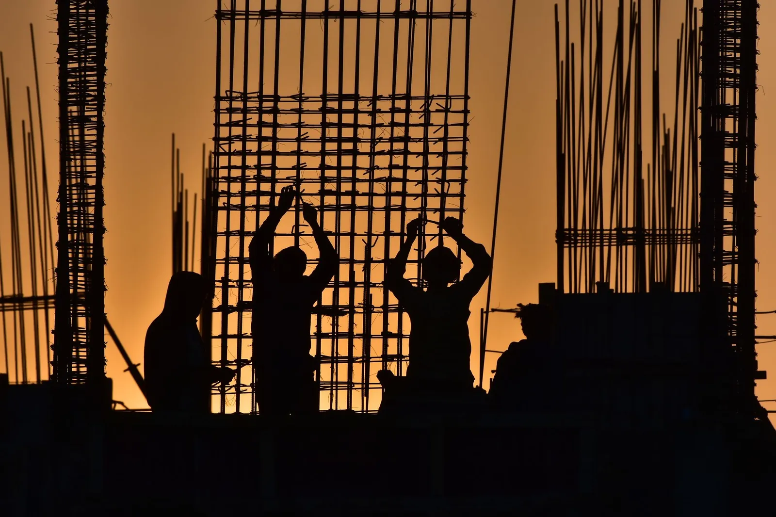 Silhouetted construction workers at a site during sunset, creating a dramatic scene. Stock photo illustrating Conart Engineers' new order story.