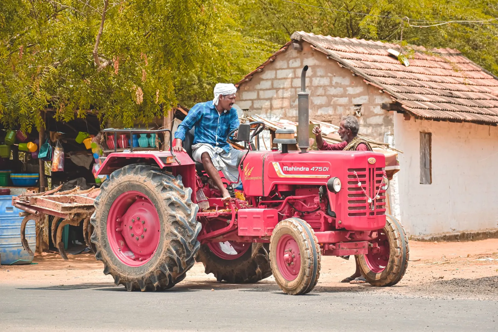 A farmer driving a red Mahindra tractor in Aranthangi, Tamil Nadu, India, showcasing rural life. Stock photo illustrating RNFI Services' partnership story.