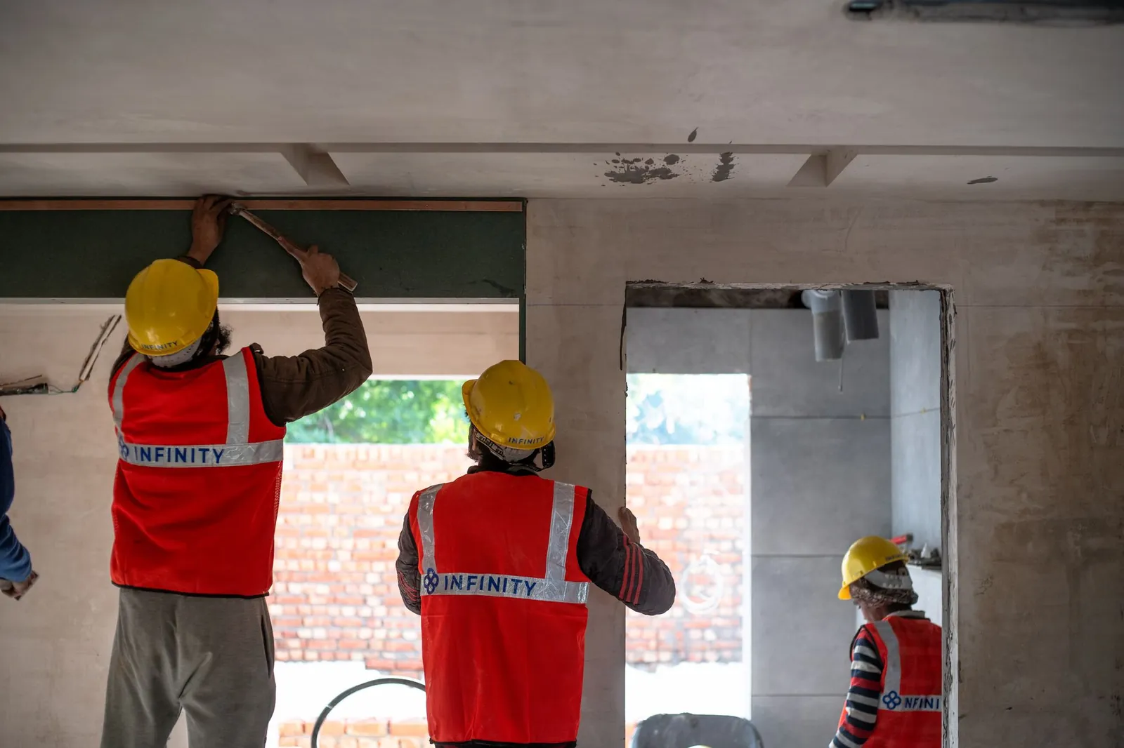 Construction workers renovating interior space in Delhi with safety gear and tools. Stock photo illustrating Neueon Corporation's new order story.