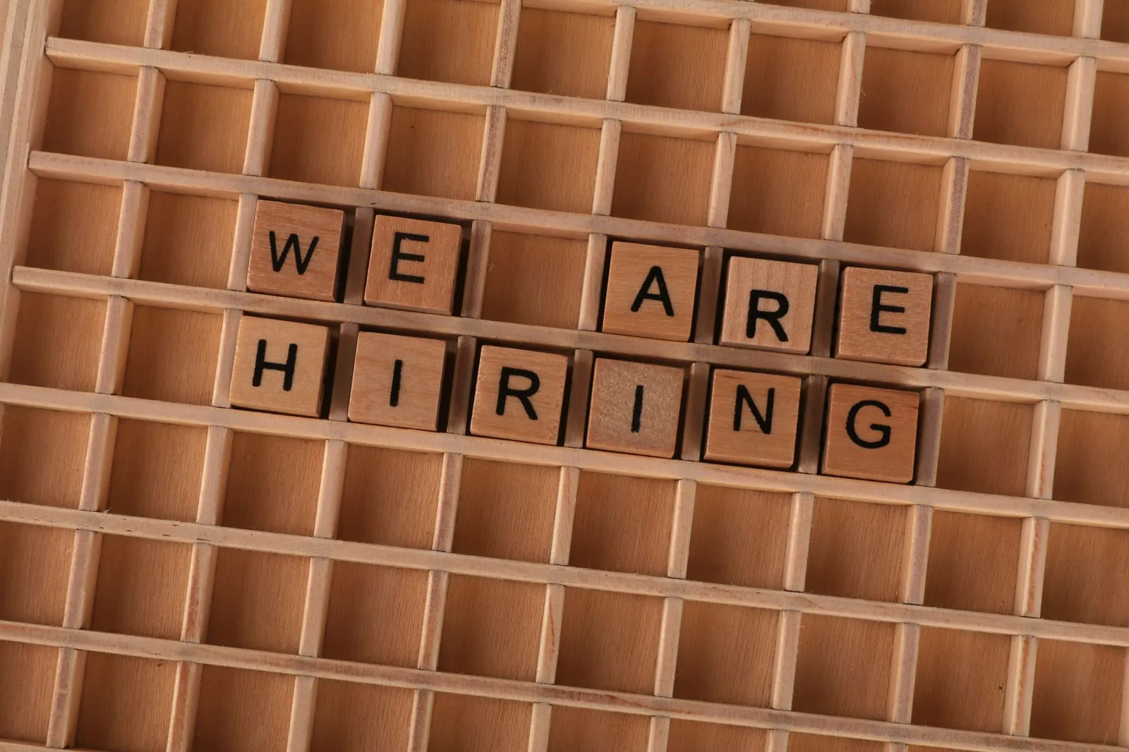 Wooden tiles on a board forming the phrase 'We Are Hiring', ideal for job announcements. Stock photo for the ALFA News guide: NSE Corporate Announcement Categories: A Guide for Investors.