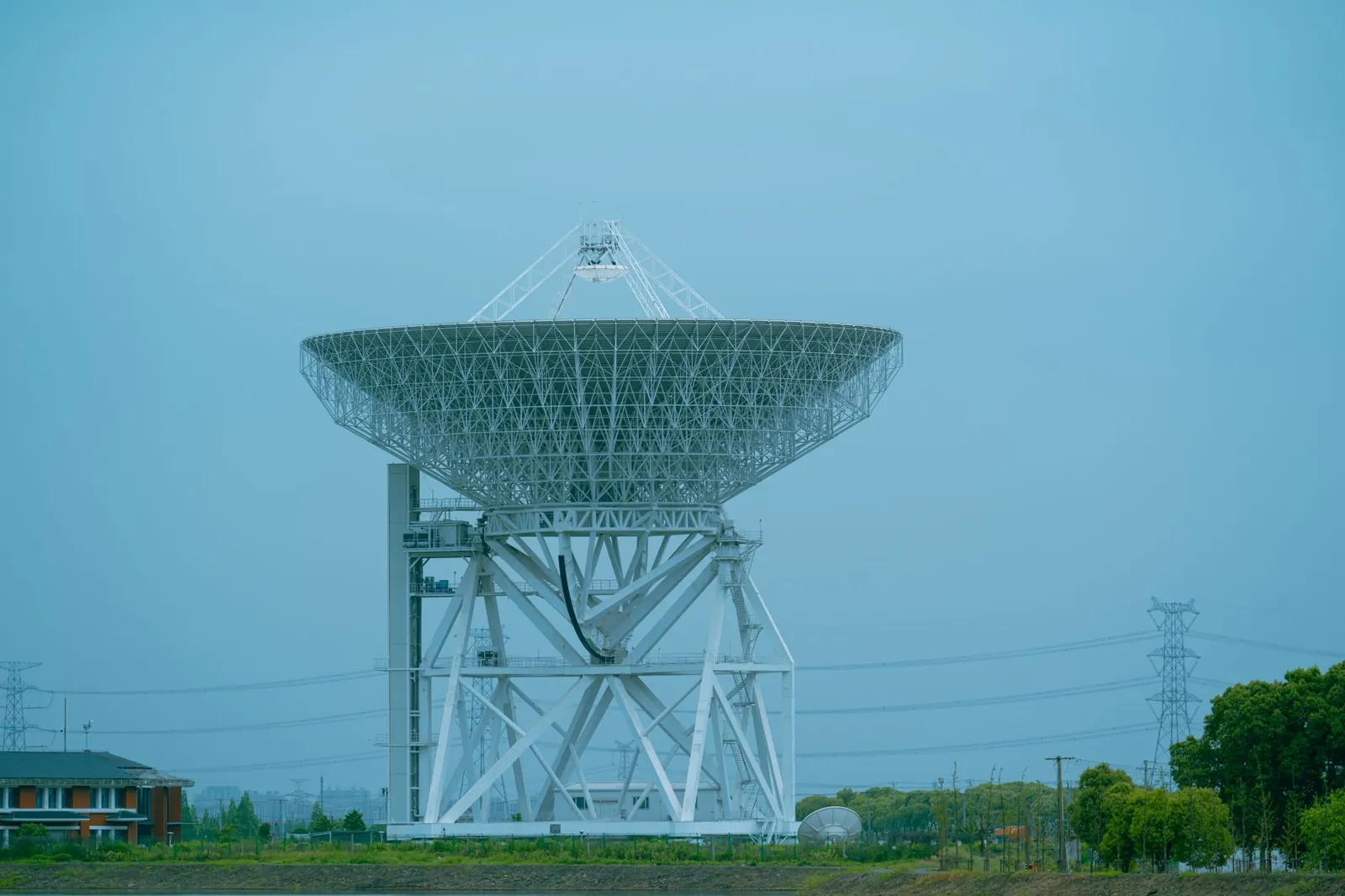 A large white satellite dish standing outdoors in a rural area, used for communication. Stock photo illustrating Avantel's new order story.