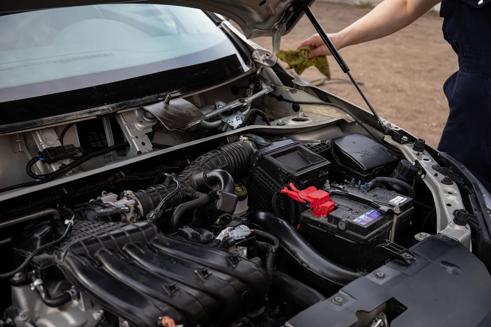 Mechanic inspecting car engine bay and battery during routine maintenance. Stock photo illustrating Amara Raja Energy & Mobility's product launched story.