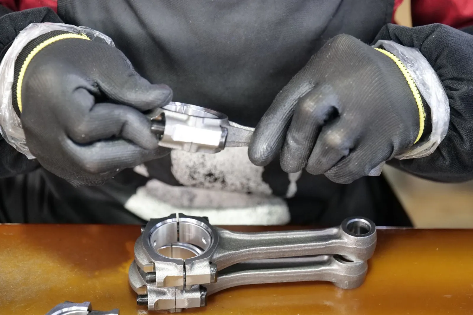 Close-up of a technician's hands assembling a metal connecting rod with precision and care. Stock photo illustrating MTAR Technologies' financial results story.
