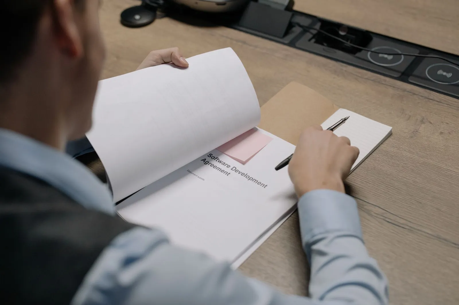 Business professional at the desk examining a software development agreement document. Stock photo illustrating IIFL Capital Services' regulatory approval story.