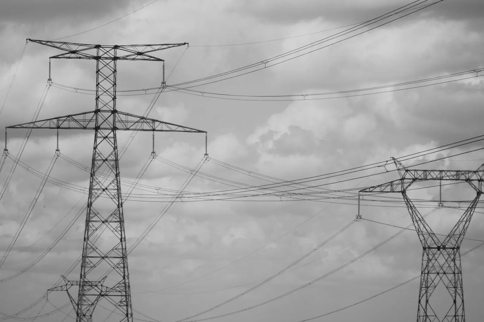 Dramatic black and white photo of high voltage power lines in the sky, showcasing industrial steel structures. Stock photo illustrating Yash Highvoltage's partnership story.