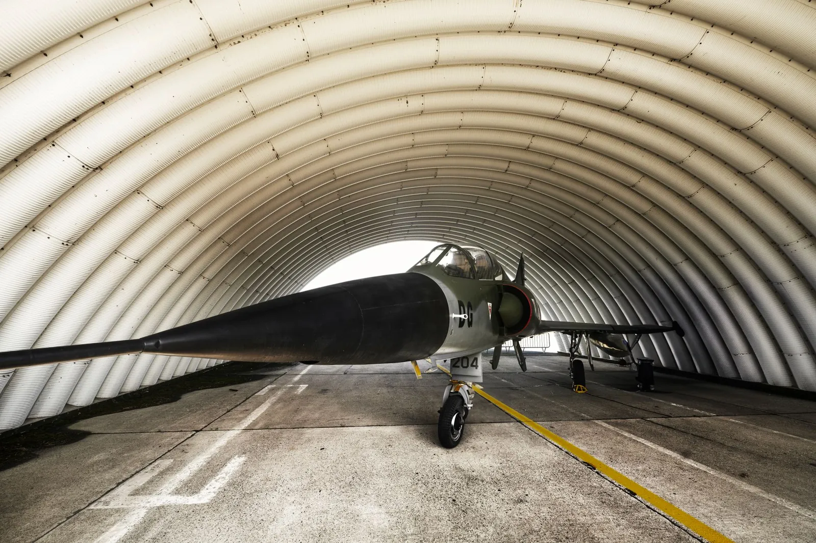 A fighter jet parked inside an arched military hangar, showcasing its sleek design. Stock photo illustrating Zen Technologies' financial results story.