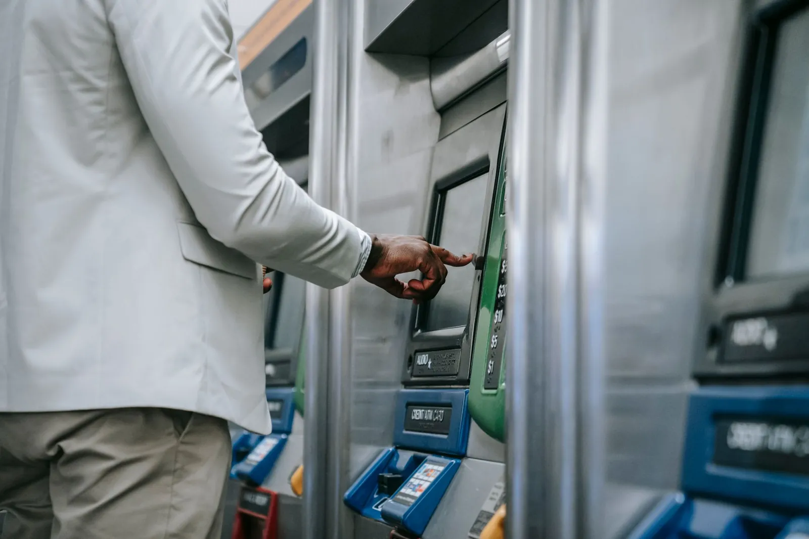 Side view of an adult using a self-service ticket machine indoors. Stock photo illustrating CMS Info Systems' new order story.