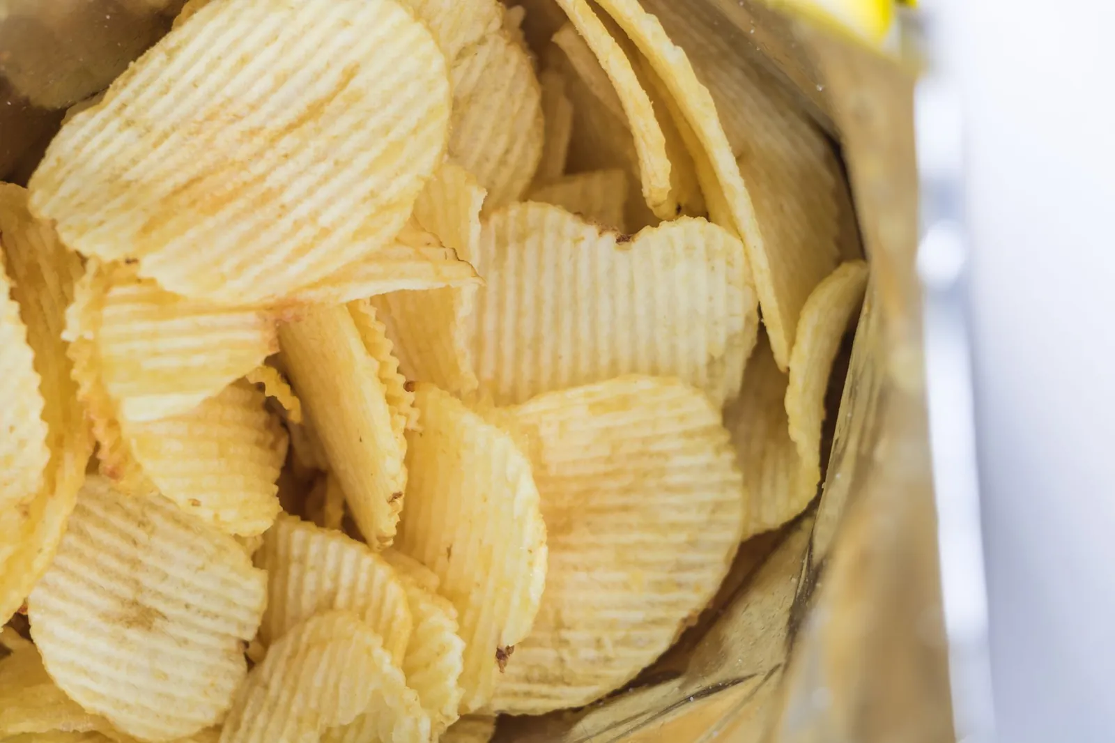 Close-up of ridged potato chips inside an opened snack bag, ready to eat. Stock photo illustrating Parag Milk Foods' product launched story.