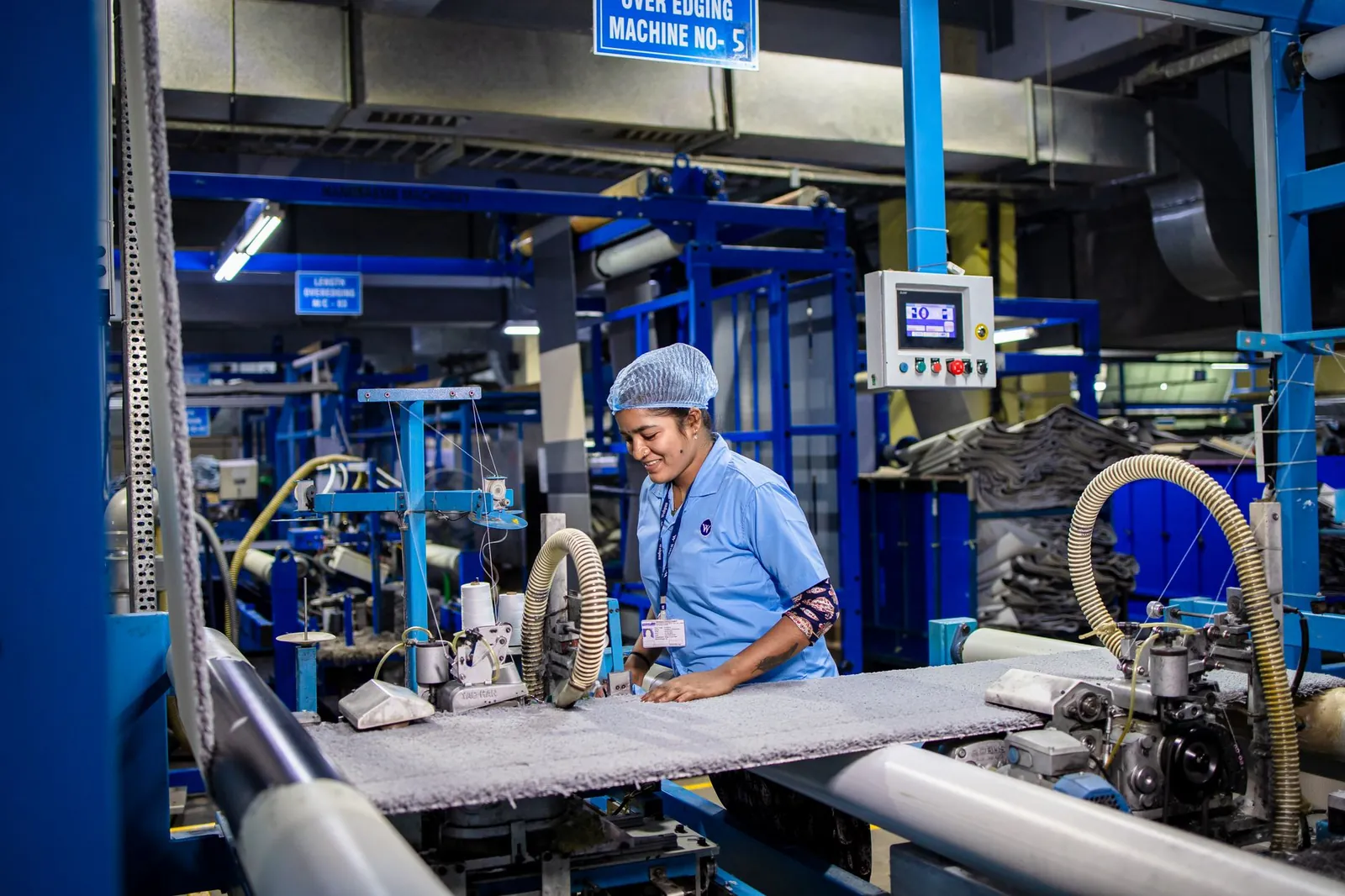 Female textile worker operating machinery in an Indian factory, showcasing industrial production. Stock photo illustrating Apsis Aerocom's expansion story.