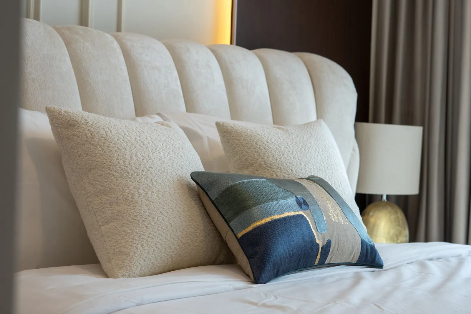 Stylish bedroom setting featuring a luxurious headboard and textured pillows for a modern look. Stock photo illustrating Encompass Design India's product launched story.