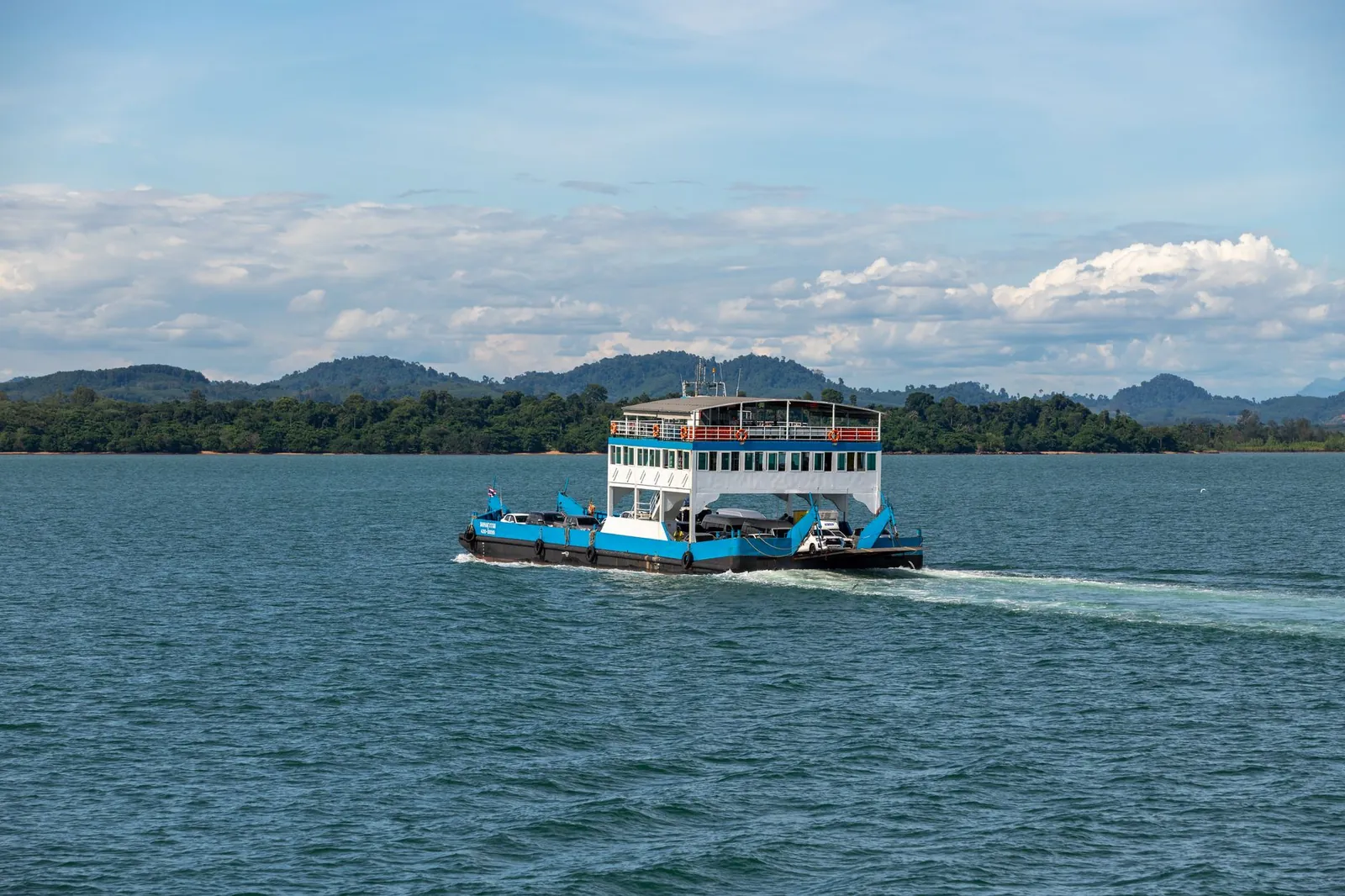 Passenger ferry traverses calm tropical waters with lush islands in the background under a clear blue sky. Stock photo illustrating Knowledge Marine & Engineering Works' new order story.
