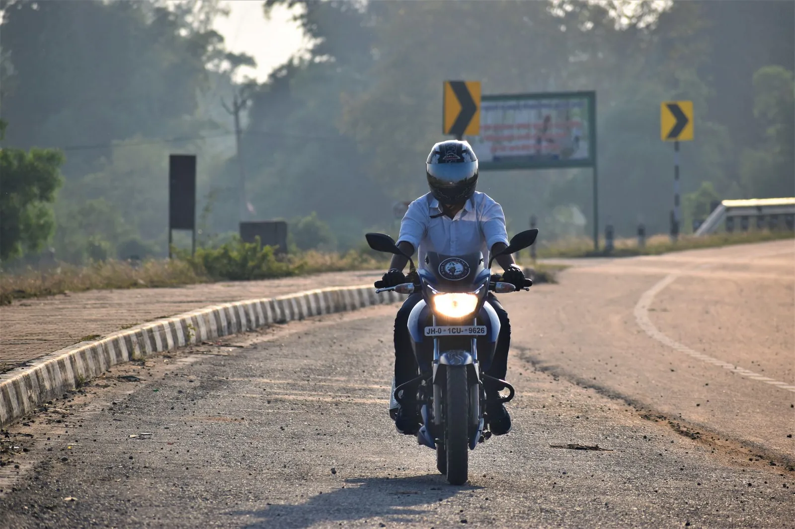A motorcyclist wearing a helmet rides down a rural road in Ranchi, India. Captured in daylight. Stock photo illustrating TVS Motor Company's product launched story.