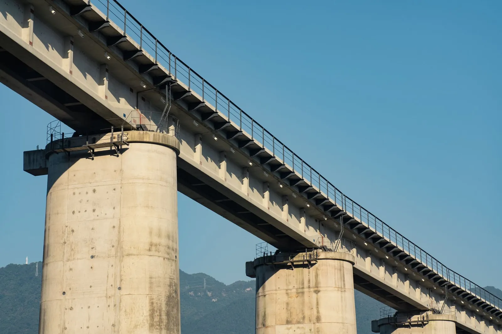 Concrete bridge with pillars against a backdrop of mountains and clear blue sky, showcasing modern architecture. Stock photo illustrating SRM Contractors' earning call story.