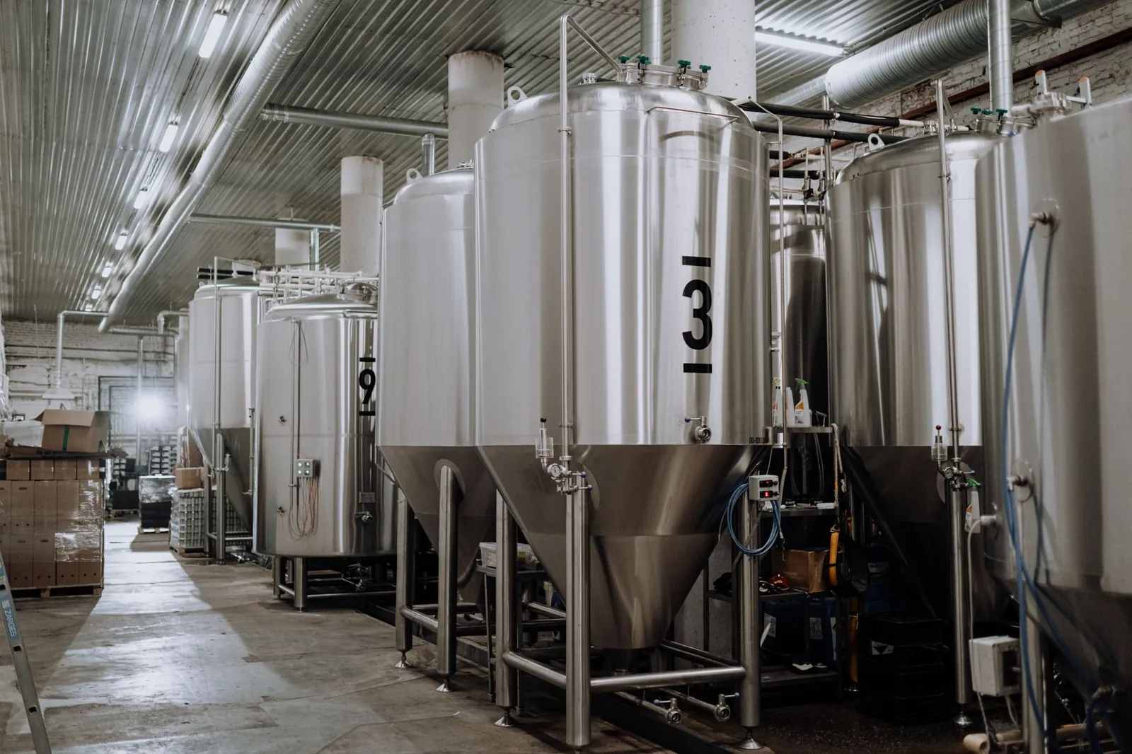 Interior view of a modern brewery showcasing stainless steel fermentation tanks. Stock photo illustrating Gujarat Themis Biosyn's fund raise story.