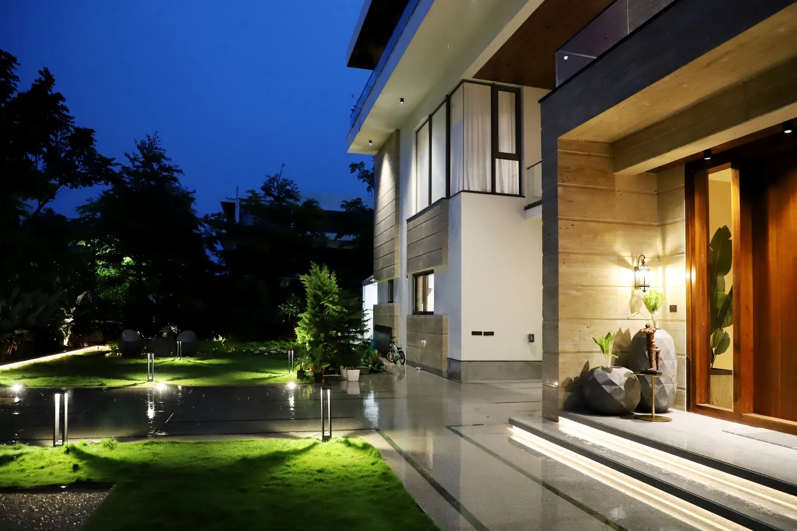 Elegant residential architecture illuminated at night, showcasing modern design and lush garden. Stock photo illustrating Puravankara's earning call story.