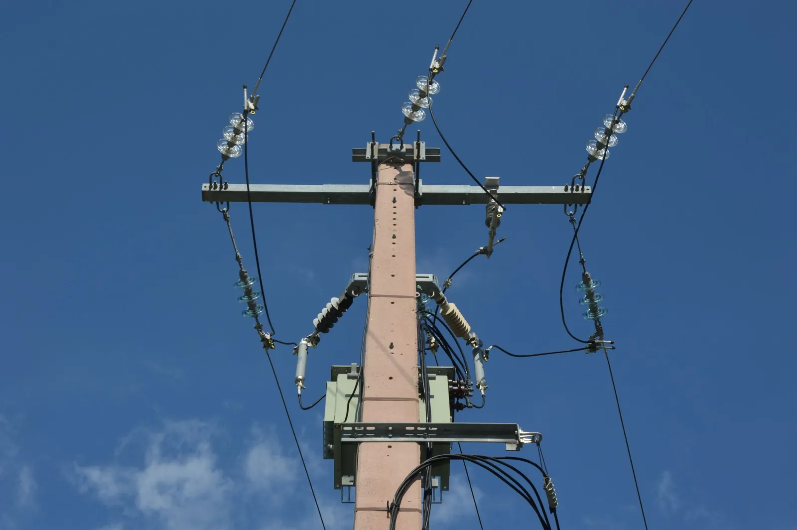 Low angle view of a utility pole with power lines against a blue sky. Stock photo illustrating Supreme Power Equipment's earning call story.