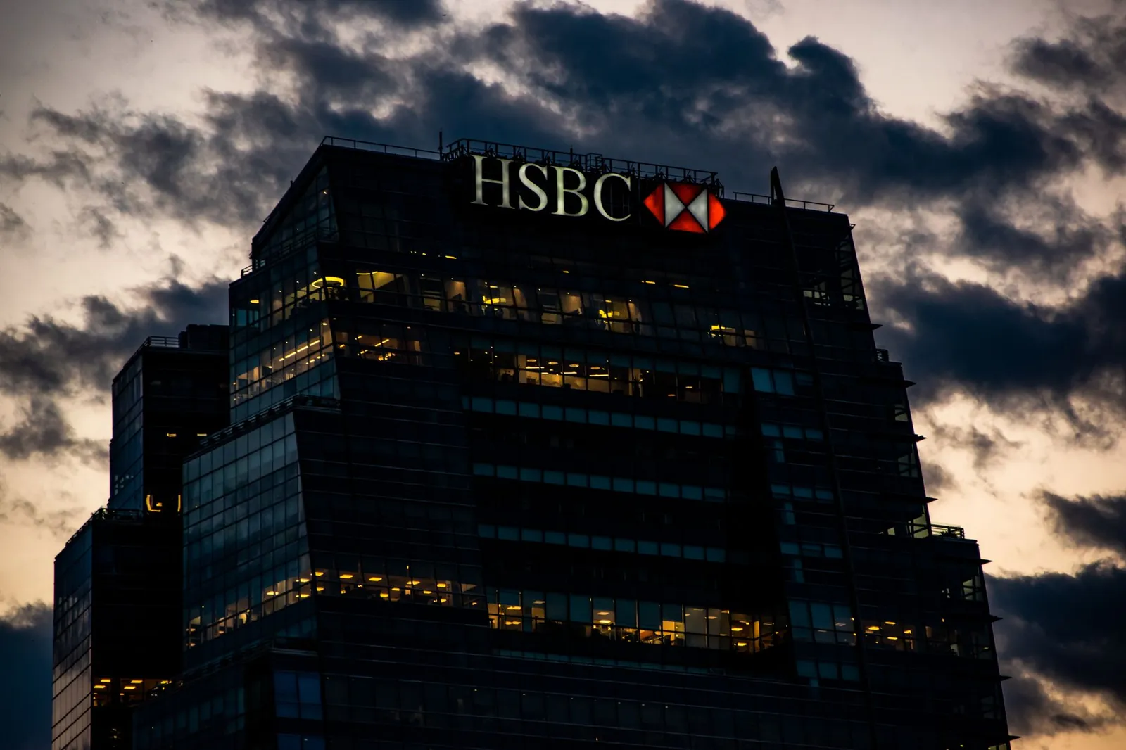 Night view of an illuminated HSBC office building against a dramatic evening sky. Stock photo illustrating ICICI Prudential Life Insurance Company's promoter buying story.