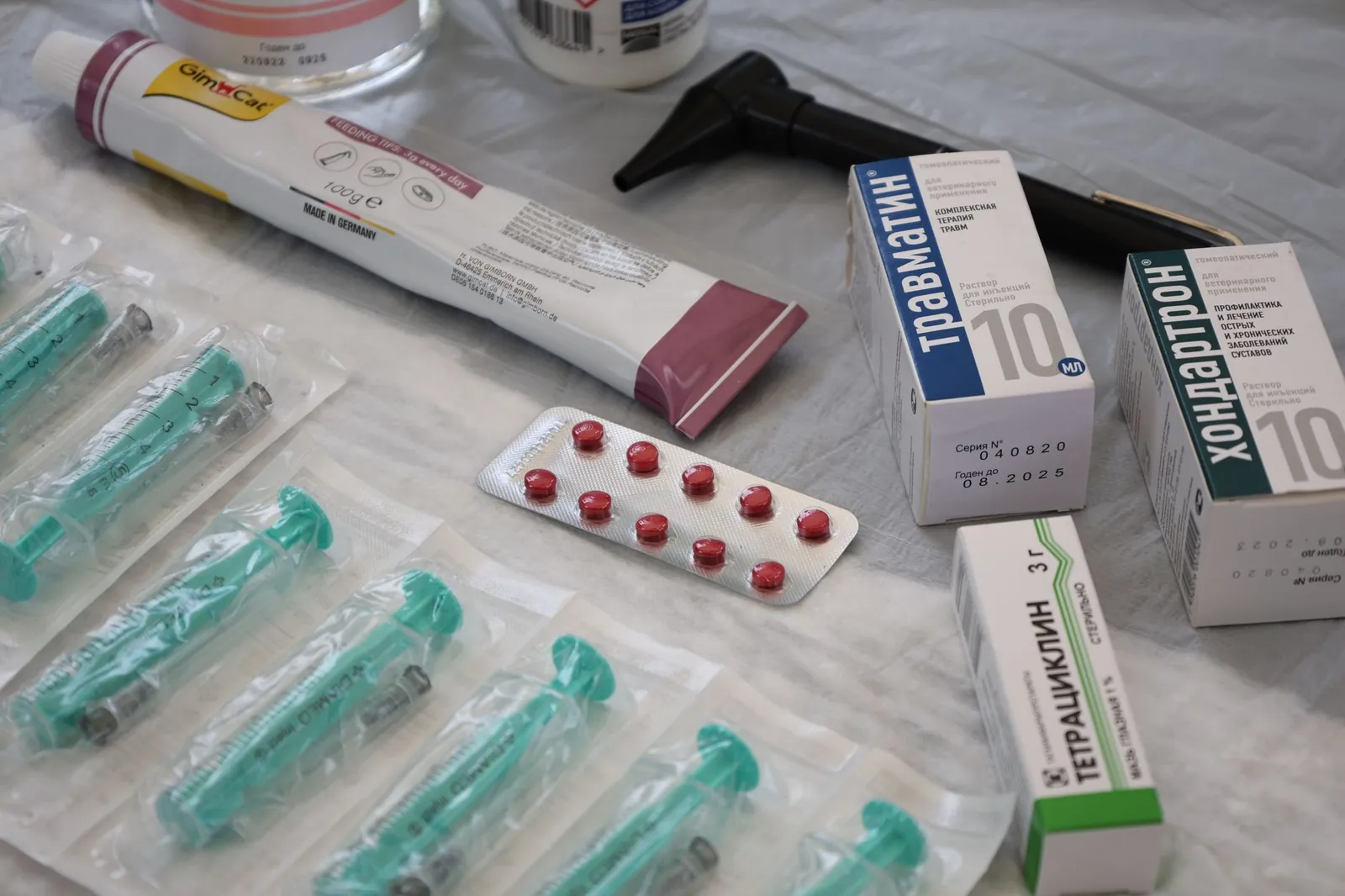 Flat lay of medical supplies including syringes, pharmaceuticals, and an otoscope on a table. Stock photo illustrating NGL Fine Chem's production started story.