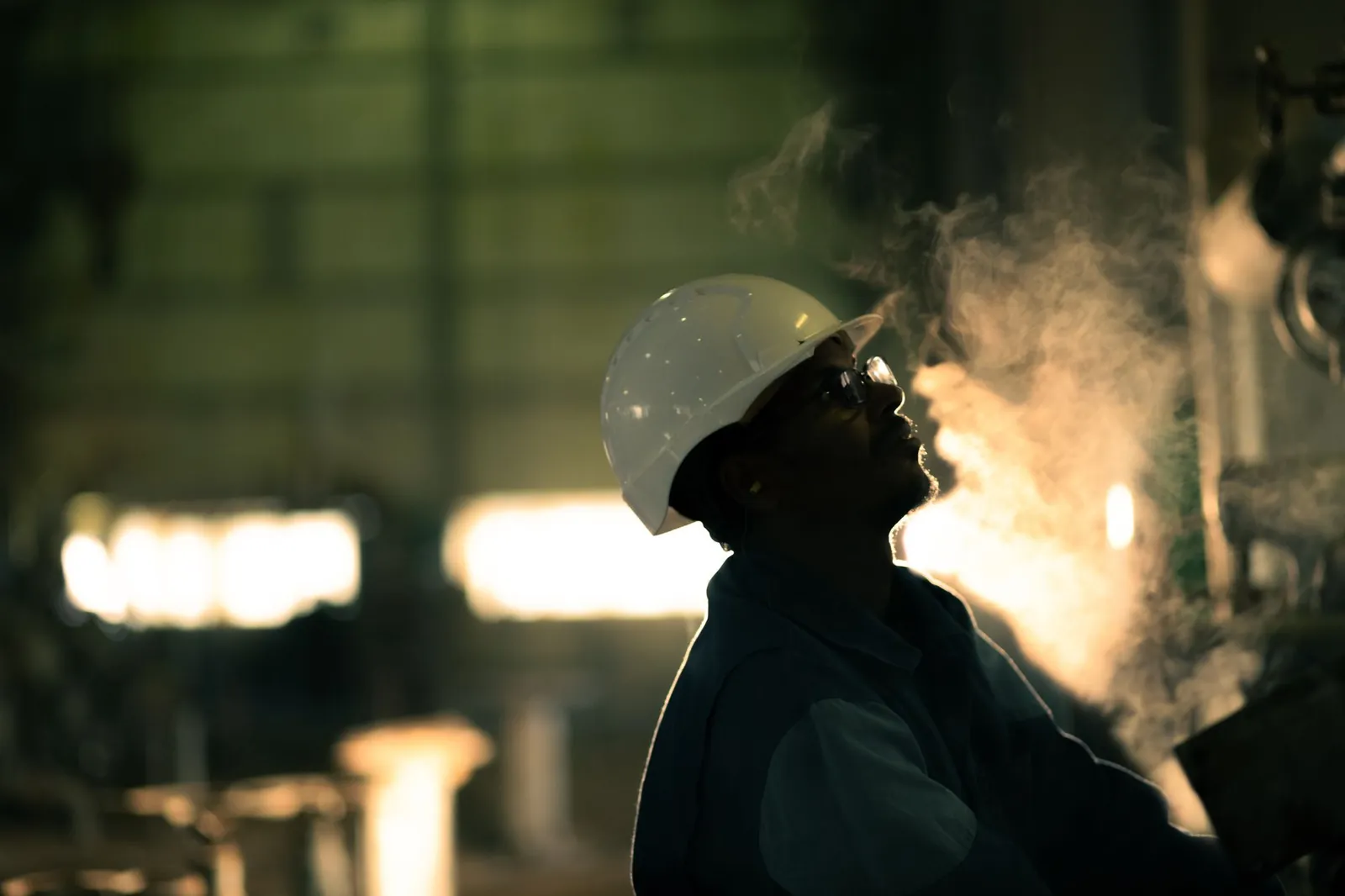 A worker in hard hat surrounded by steam in an industrial setting, conveying energy industry. Stock photo illustrating Steamhouse India's new order story.