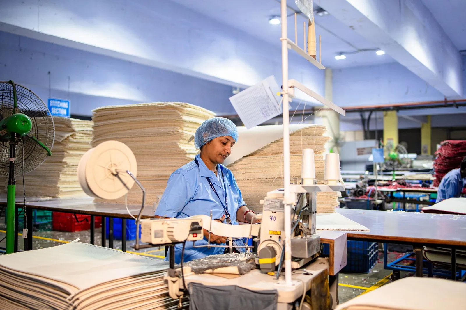 A female worker sewing in a textile factory, showcasing industrial production processes. Stock photo illustrating Shilpa Medicare's production started story.
