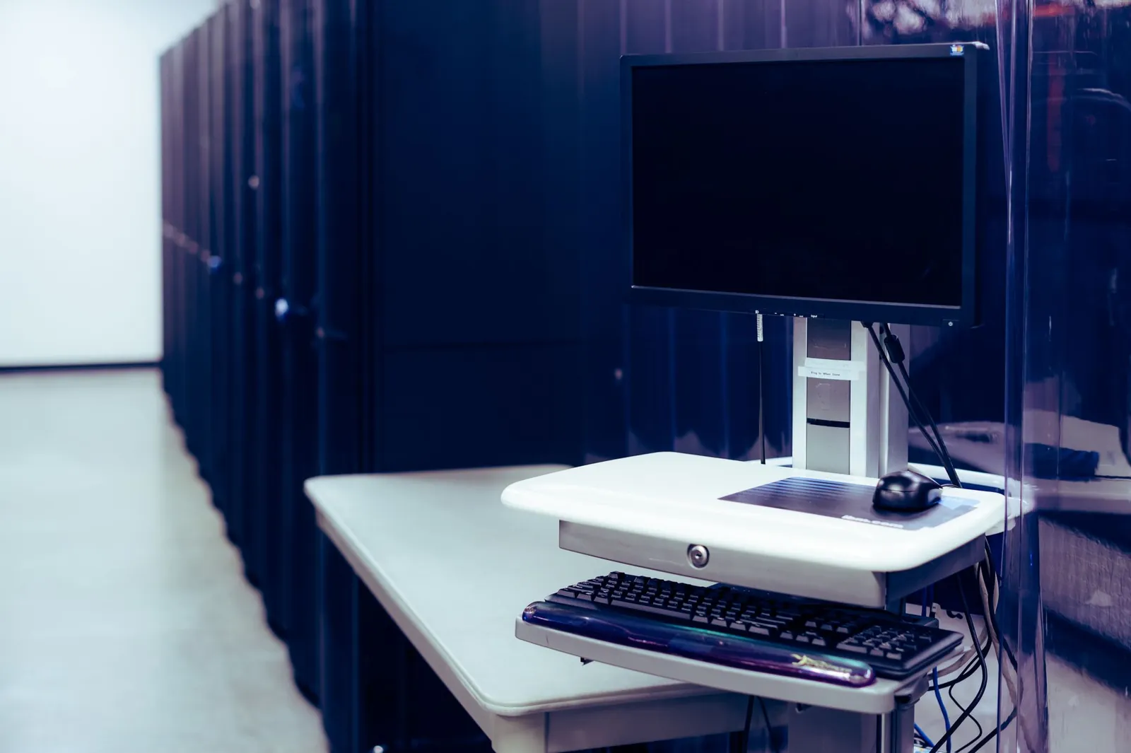 Contemporary computer with black screen placed on stand near row of server steel racks in data center. Stock photo illustrating Bharti Airtel's product launched story.