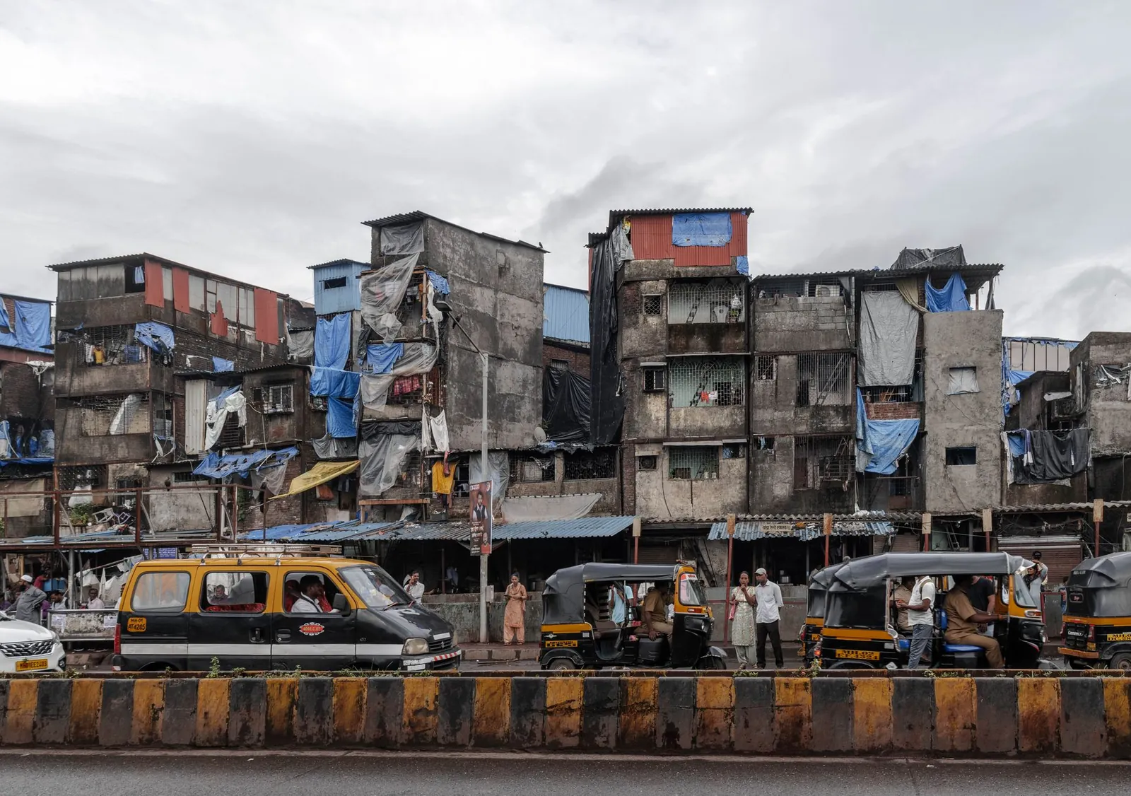 Street scene in Mumbai, showcasing auto rickshaws and residential buildings on a cloudy day. Stock photo illustrating Capacit'e Infraprojects' new order story.