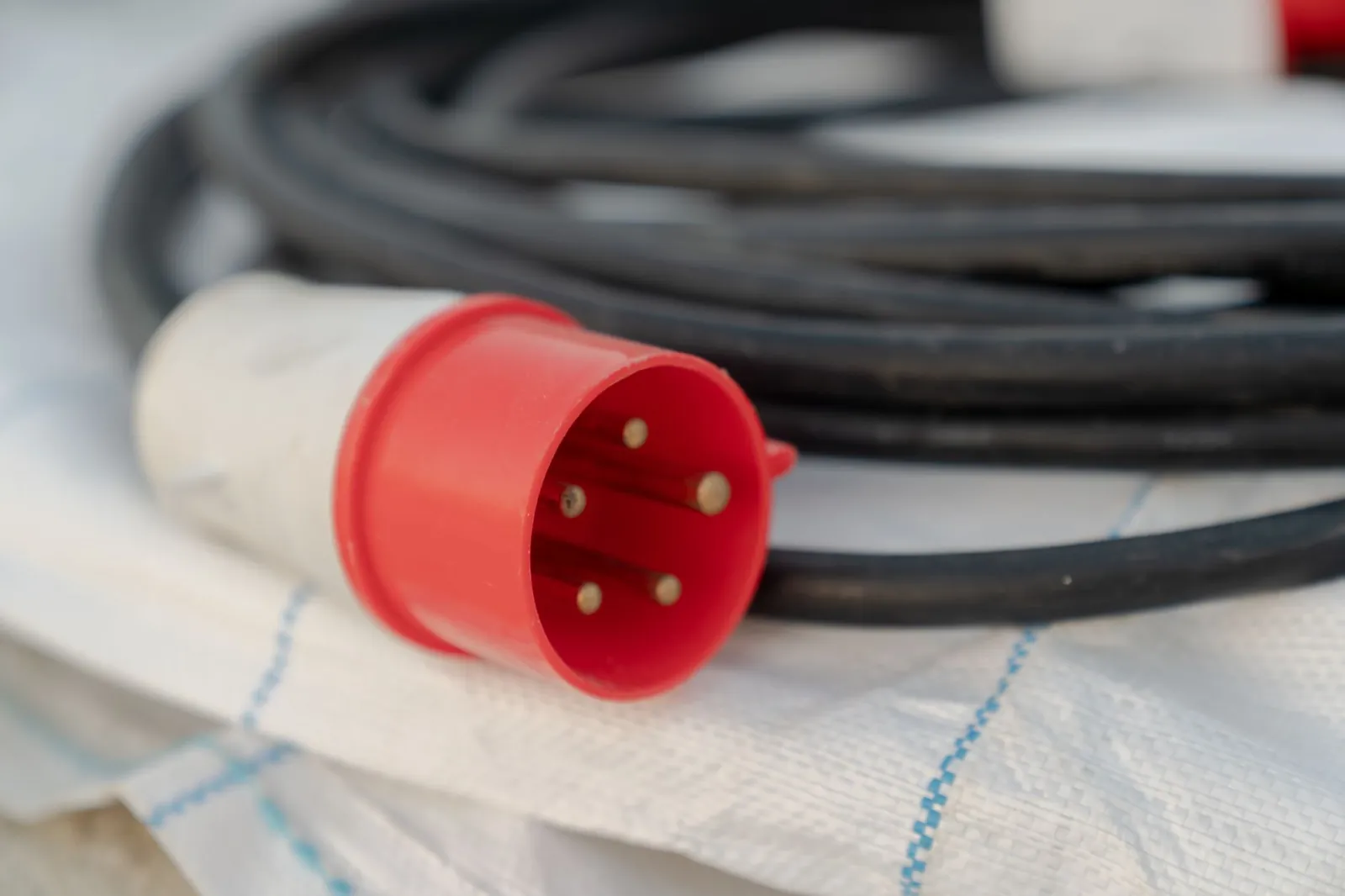 Detailed view of a red industrial electrical cable plug with visible pins. Stock photo illustrating Delton Cables' earning call story.