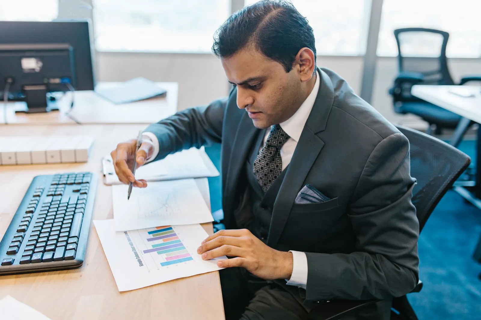 Business professional reviewing graphs and charts on a desk in a modern office setting. Stock photo illustrating Piramal Finance's earning call story.