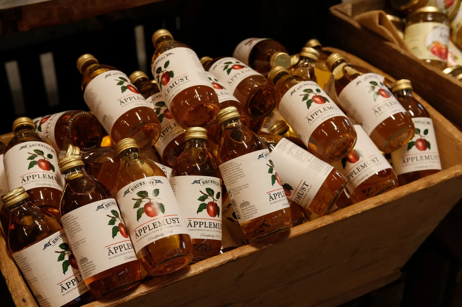 A variety of bottled apple juice arranged in a wooden crate, perfect for market displays. Stock photo illustrating Kothari Industrial Corporation's product launched story.