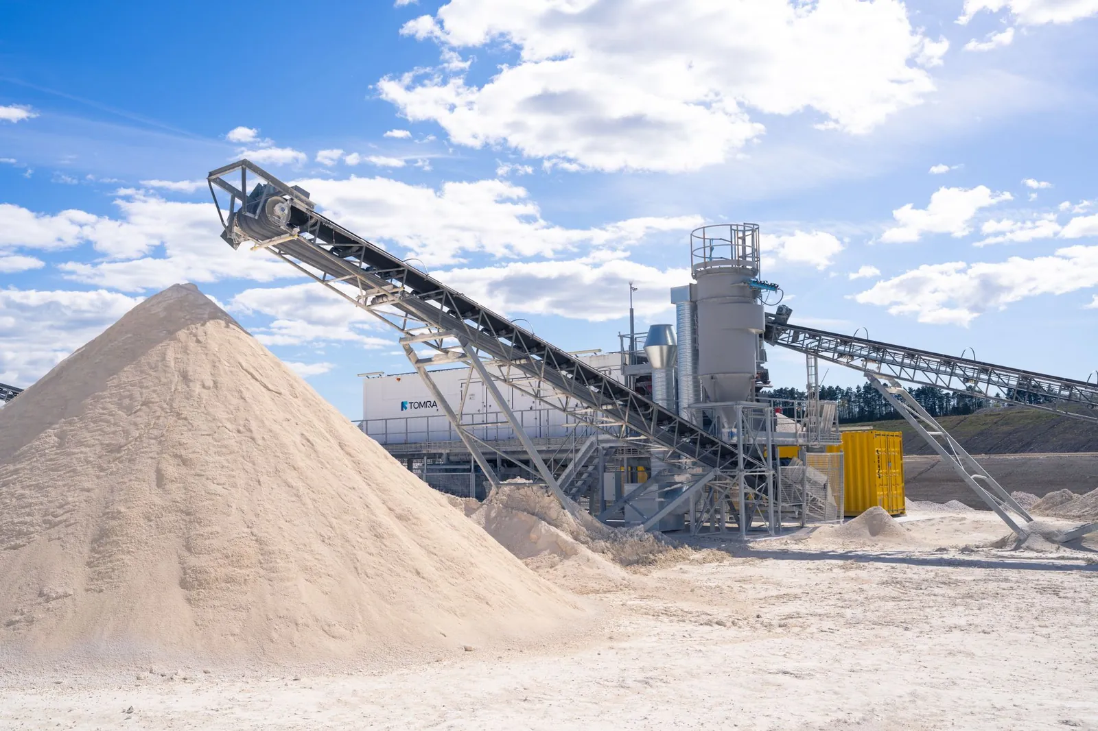 A modern sand processing plant with conveyor belts under a clear blue sky. Stock photo illustrating Monolithisch India's expansion story.
