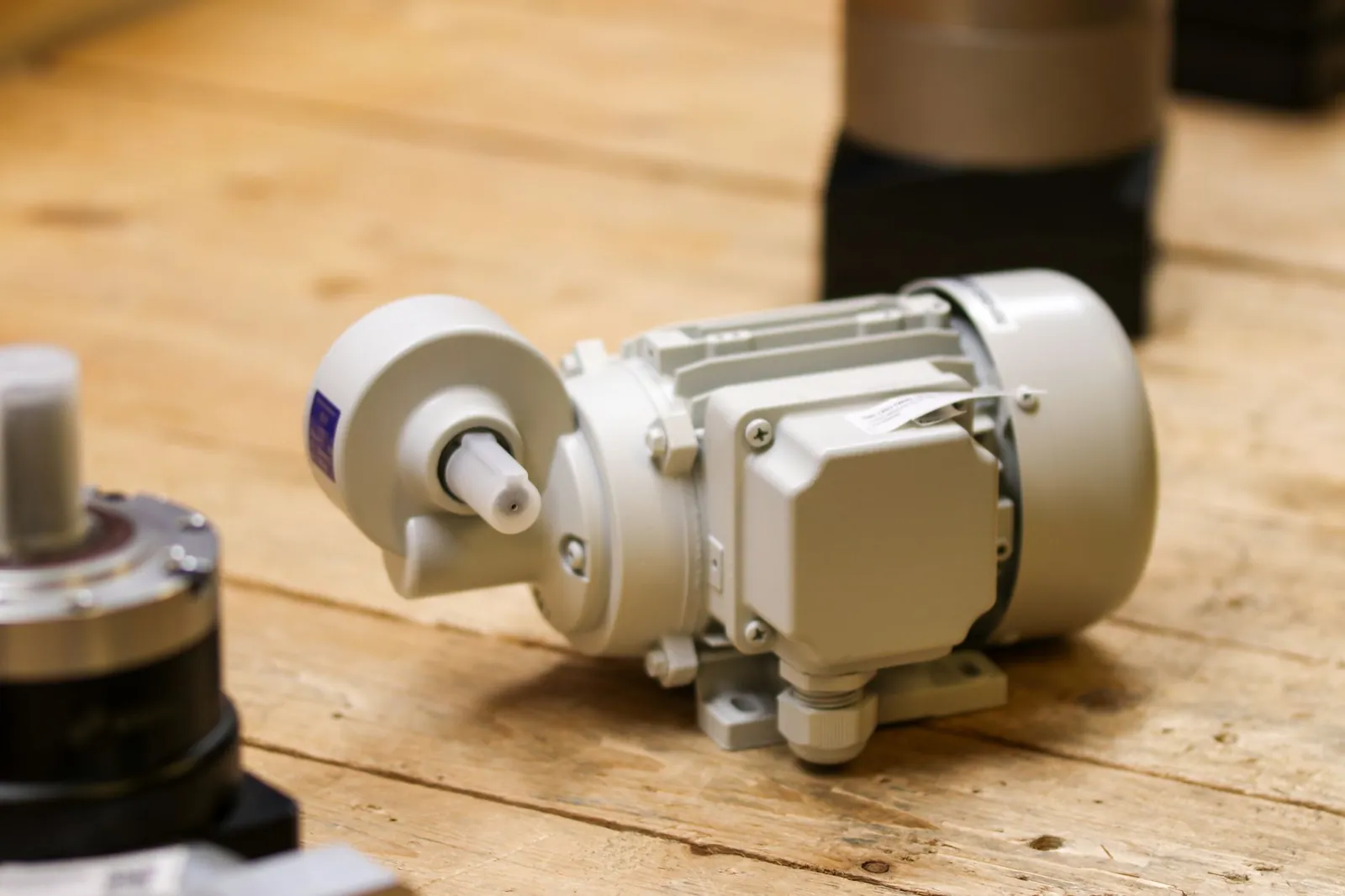 Close-up of a white industrial motor placed on a wooden surface inside a workshop. Stock photo illustrating Sona BLW Precision Forgings' earning call story.