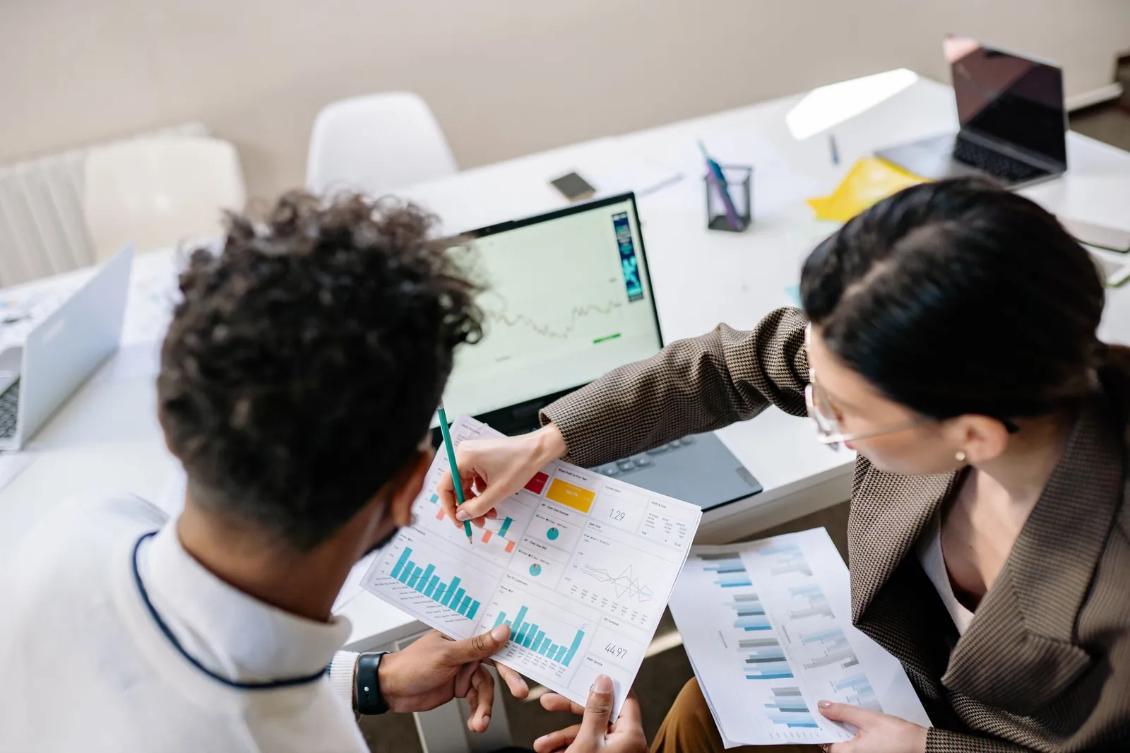 Two colleagues in a meeting room discussing financial charts and graphs on a laptop and paper. Stock photo illustrating Pelatro's fund raise story.