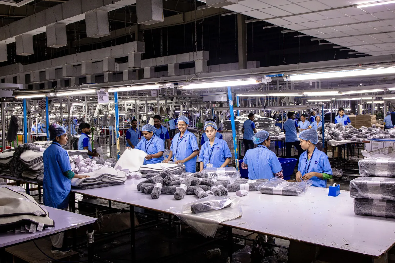 Indian textile factory workers expertly packaging products on an assembly line. Stock photo illustrating Pearl Global Industries' earning call story.