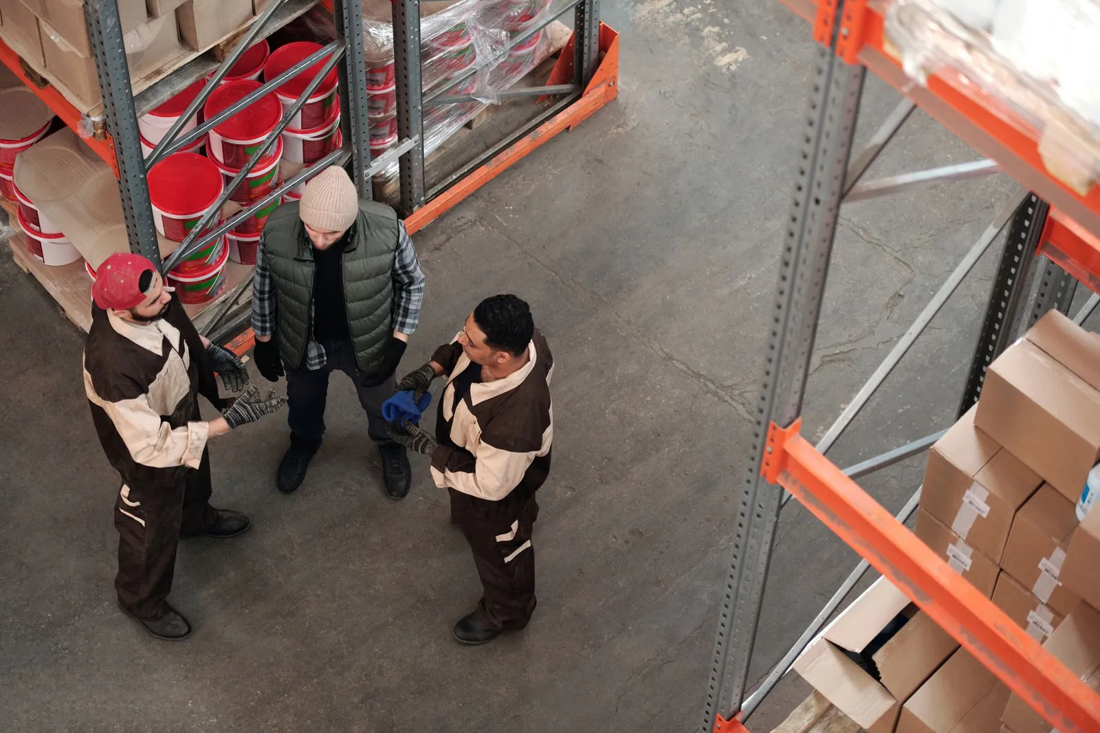 Three workers discussing logistics in an industrial warehouse setting from a high angle view. Stock photo illustrating Garware Hi-Tech Films' earning call story.