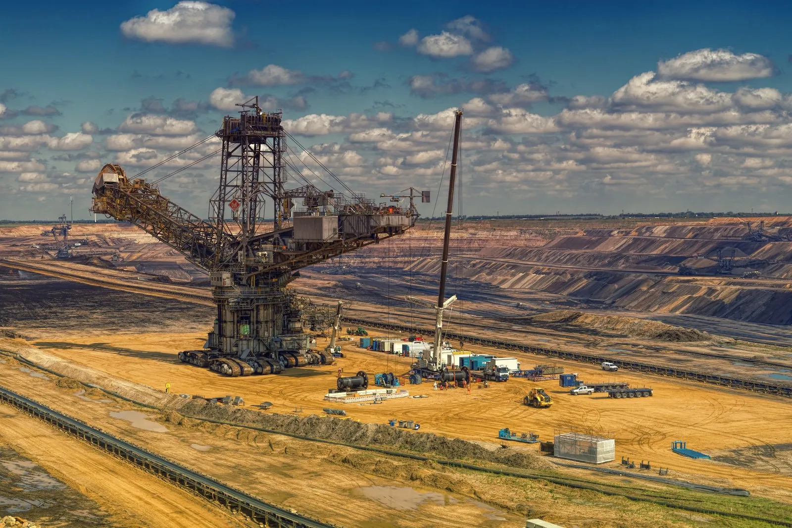 Aerial view of heavy machinery operating in a vast open-pit mine under a cloudy sky. Stock photo illustrating Steel Authority of India's partnership story.