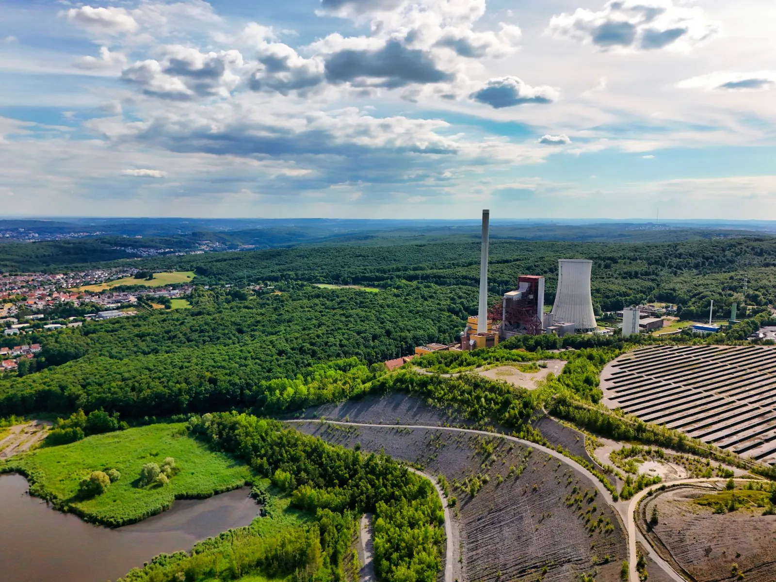 Aerial view of power plant surrounded by forests and clear skies, capturing nature-industry contrast. Stock photo illustrating AksharChem India's production started story.