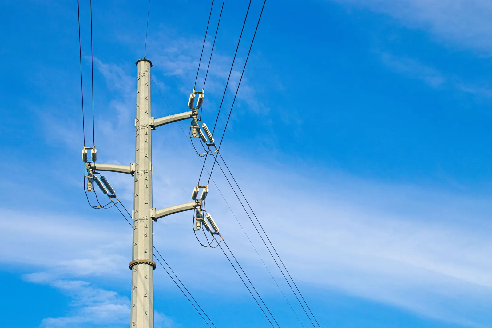 A utility pole with power lines set against a bright blue sky, representing energy infrastructure. Stock photo illustrating Marsons' new order story.