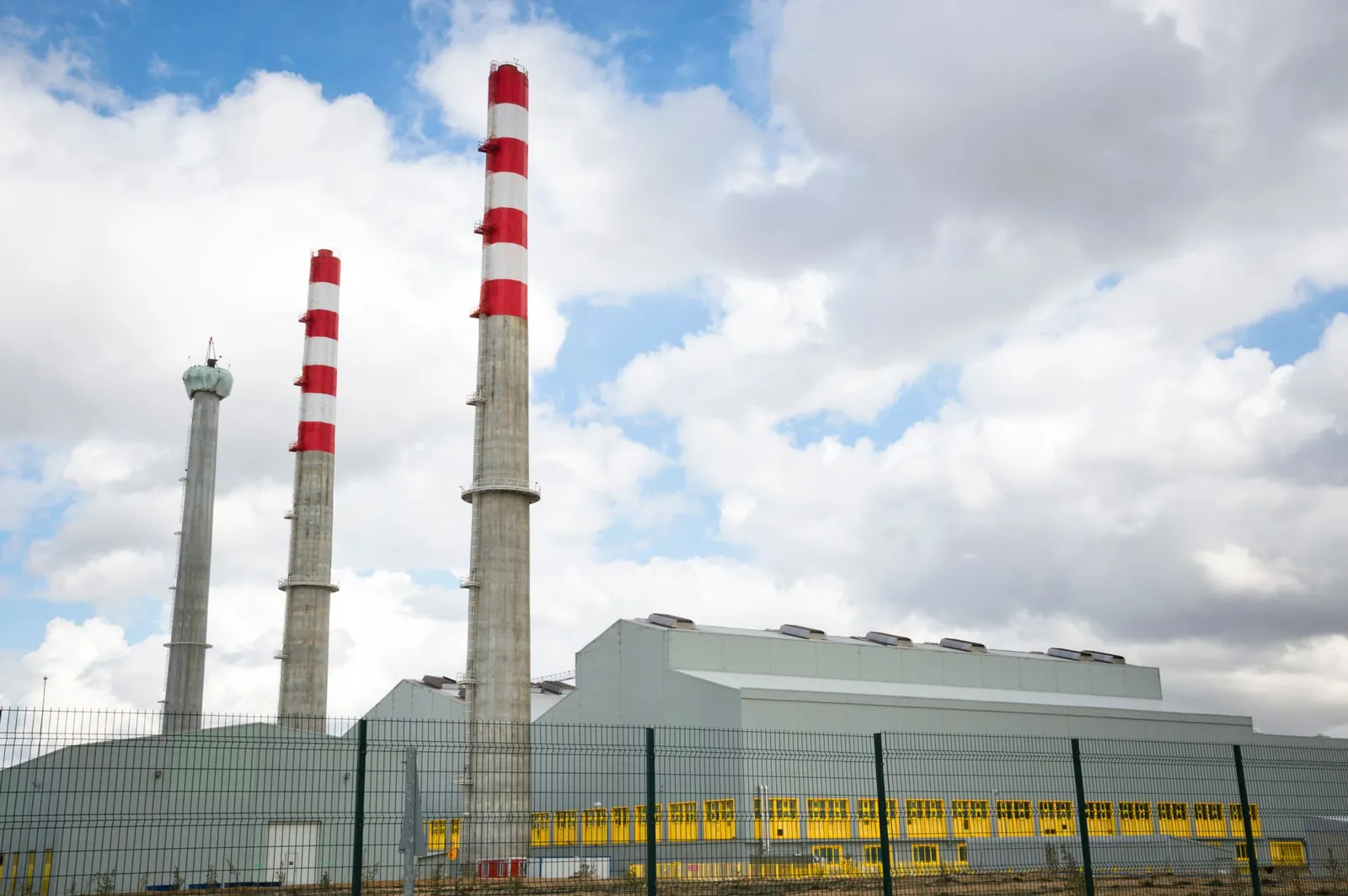 Factory chimneys against a blue sky symbolize industrial power and environmental impact. Stock photo illustrating Vipul Organics' production started story.