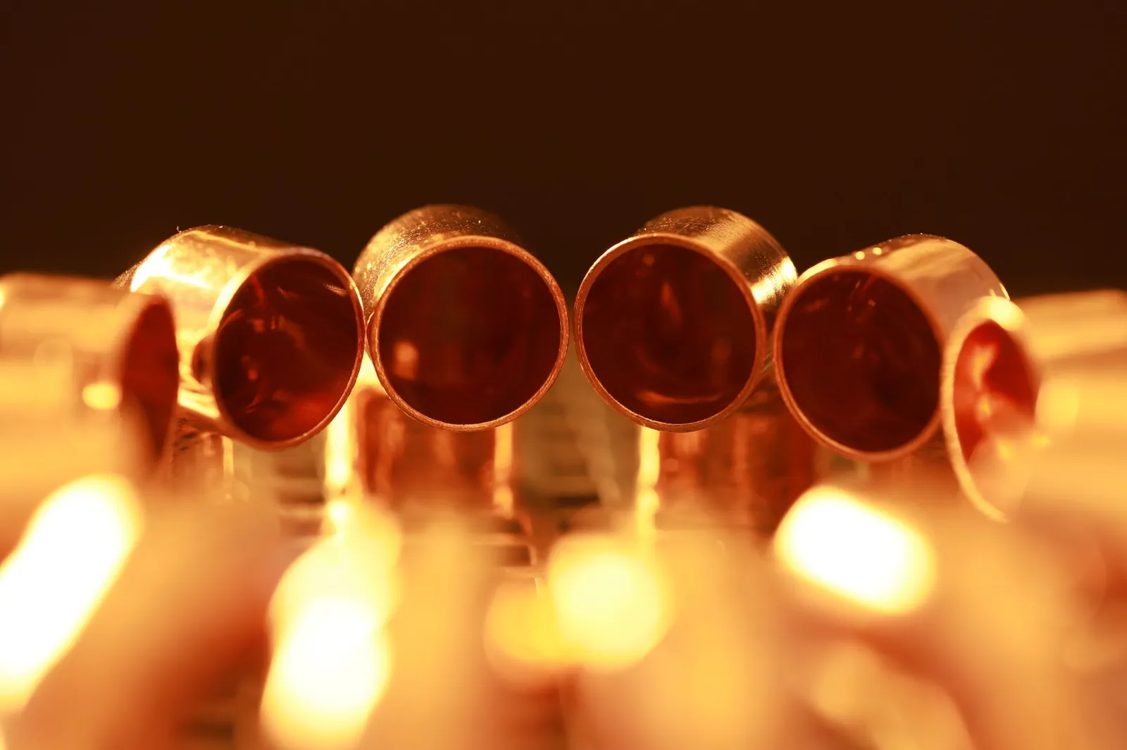 Macro shot of brass tubes with warm, glowing lighting, showcasing a serene and vintage ambiance. Stock photo illustrating Baroda Extrusion's new order story.